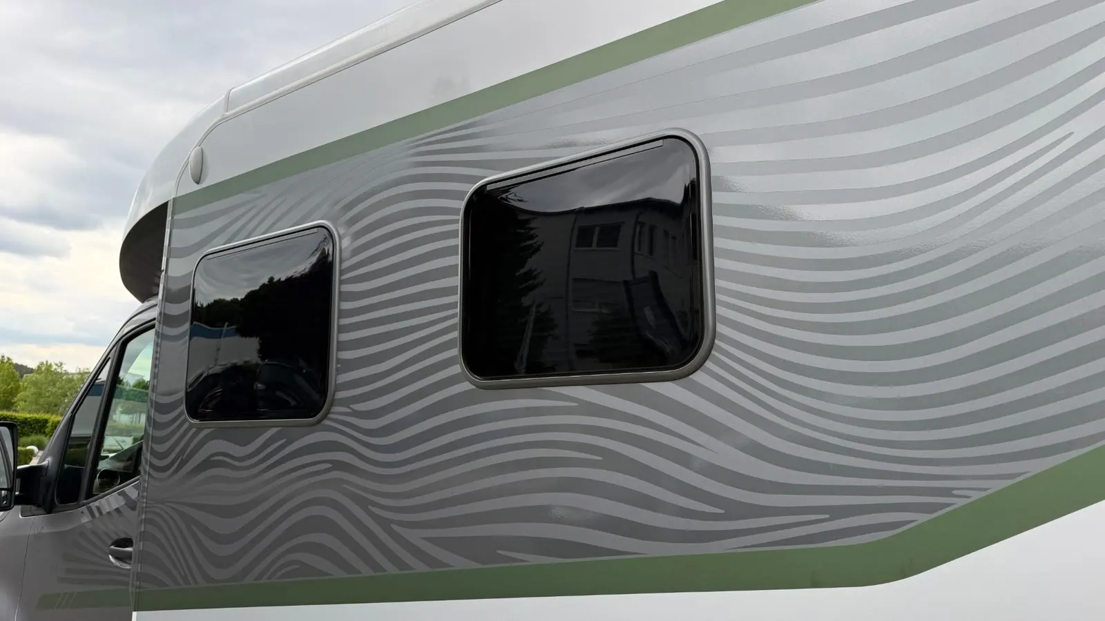 Wohnmobil mit getönten Aufbaufenstern und Wellen-Design