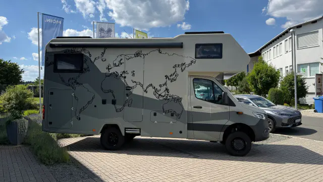 Alkoven-Wohnmobil mit Weltkarte im Skizzenstil und grafischen Farbflächen